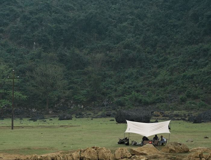 Tranquil camping setup by a serene lake surrounded by lush misty mountains.