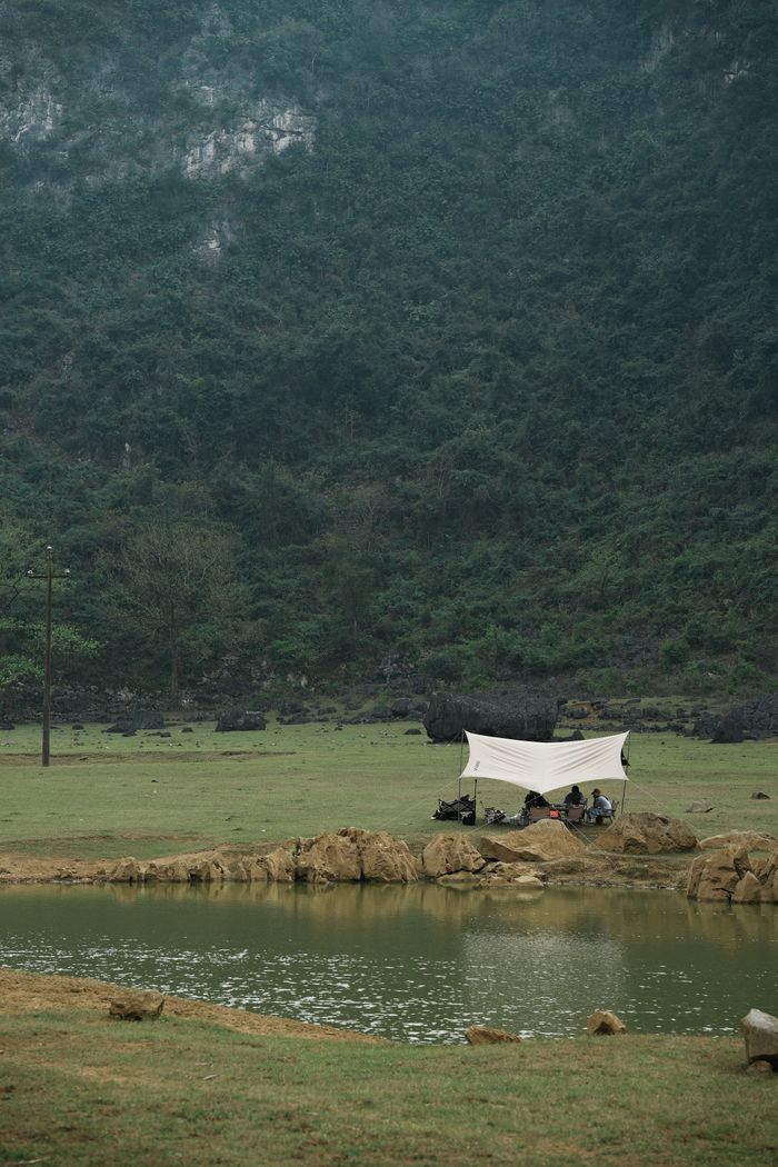 Tranquil camping setup by a serene lake surrounded by lush misty mountains.