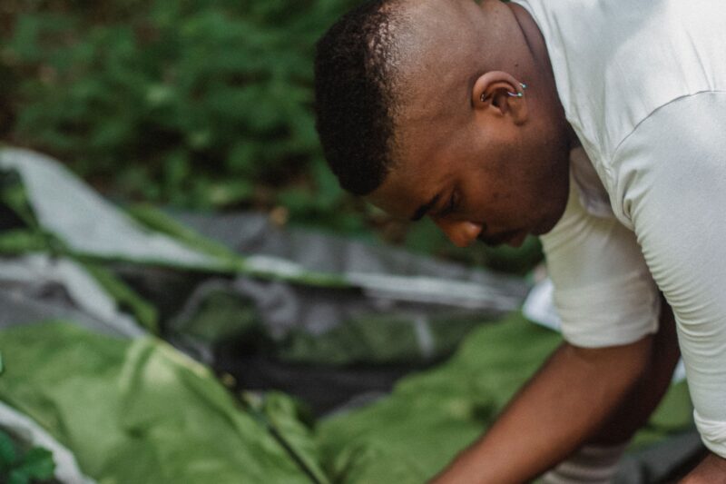 Hiker pegging down a tent guyline into the grass