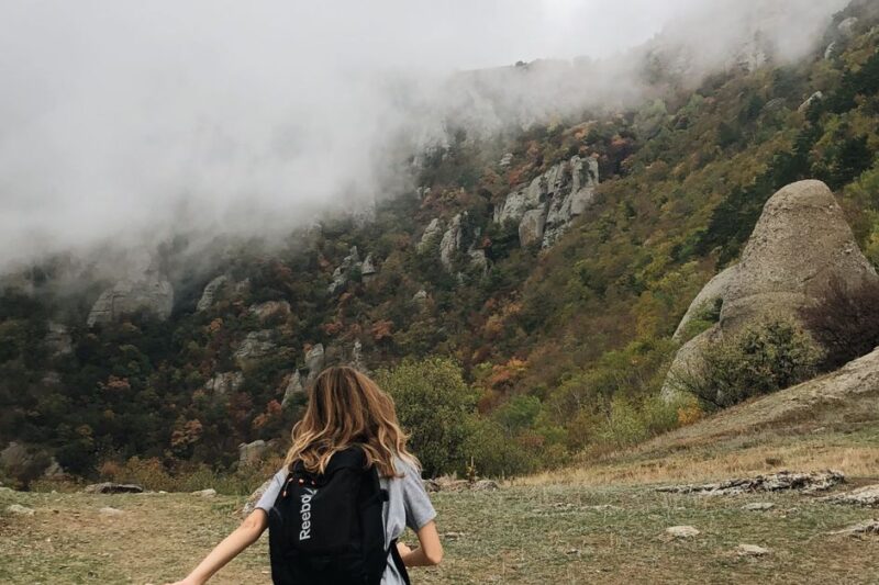 Hiker wearing layered insulation while climbing a foggy mountain trail
