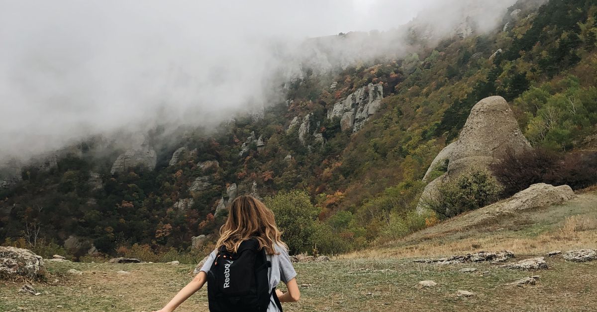 Hiker wearing layered insulation while climbing a foggy mountain trail