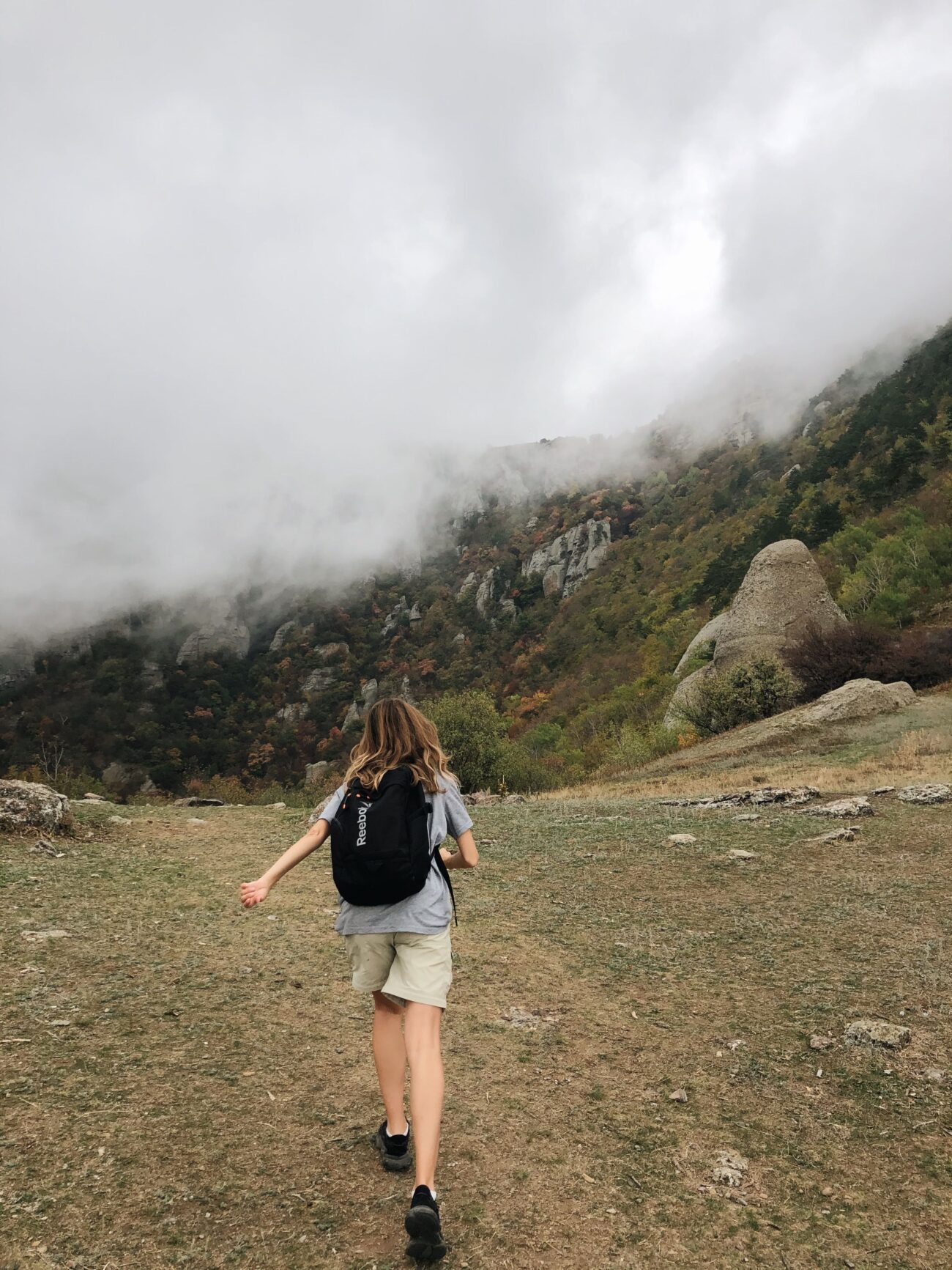 Hiker wearing a rain shell walking through foggy mountain terrain