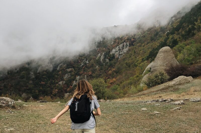 Hiker wearing a rain shell walking through foggy mountain terrain