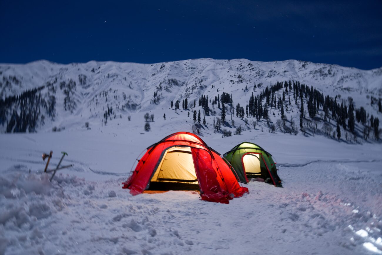 Tent pitched on snow-covered ground at night, representing cold winter backpacking conditions where vapor barrier liners help